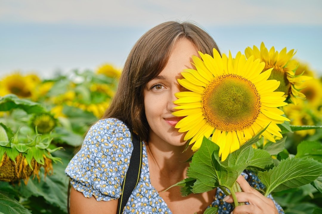 Joyful woman covers half of her face with sunflower
